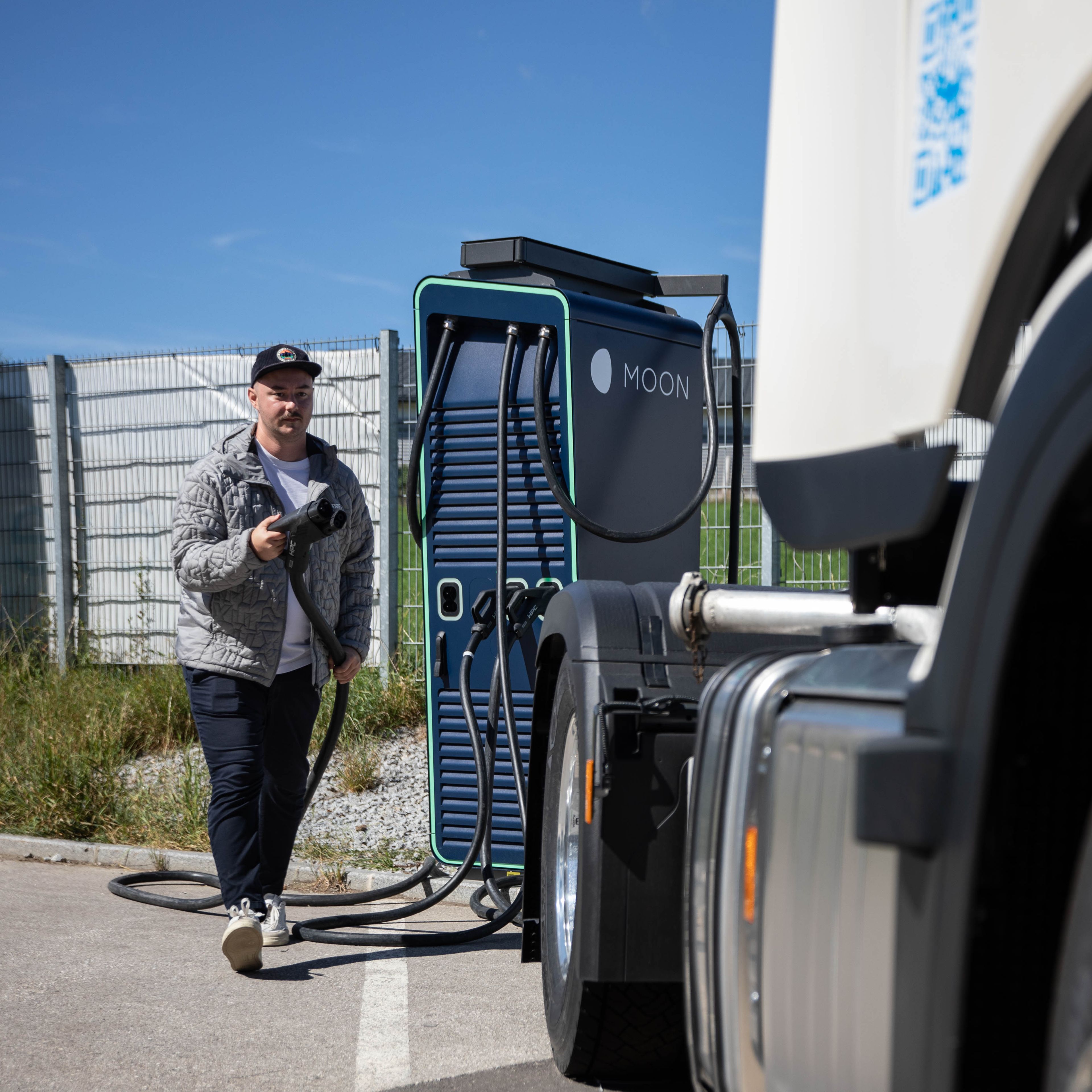 A man walks towards a truck with the plug of a HYC 200-400 fast charging station