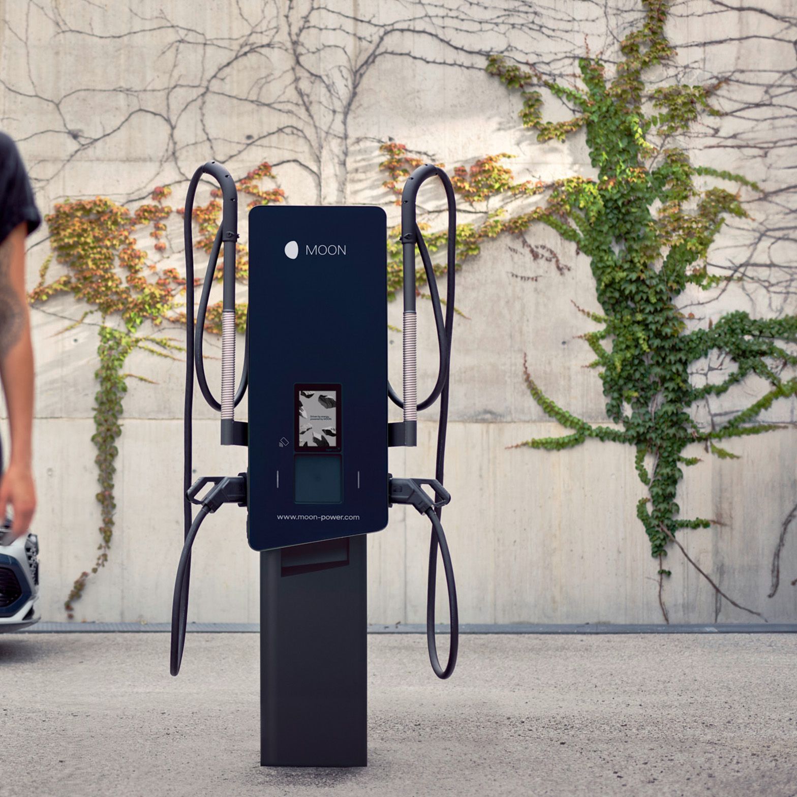 Woman walks in front of a charging station with a car in the background