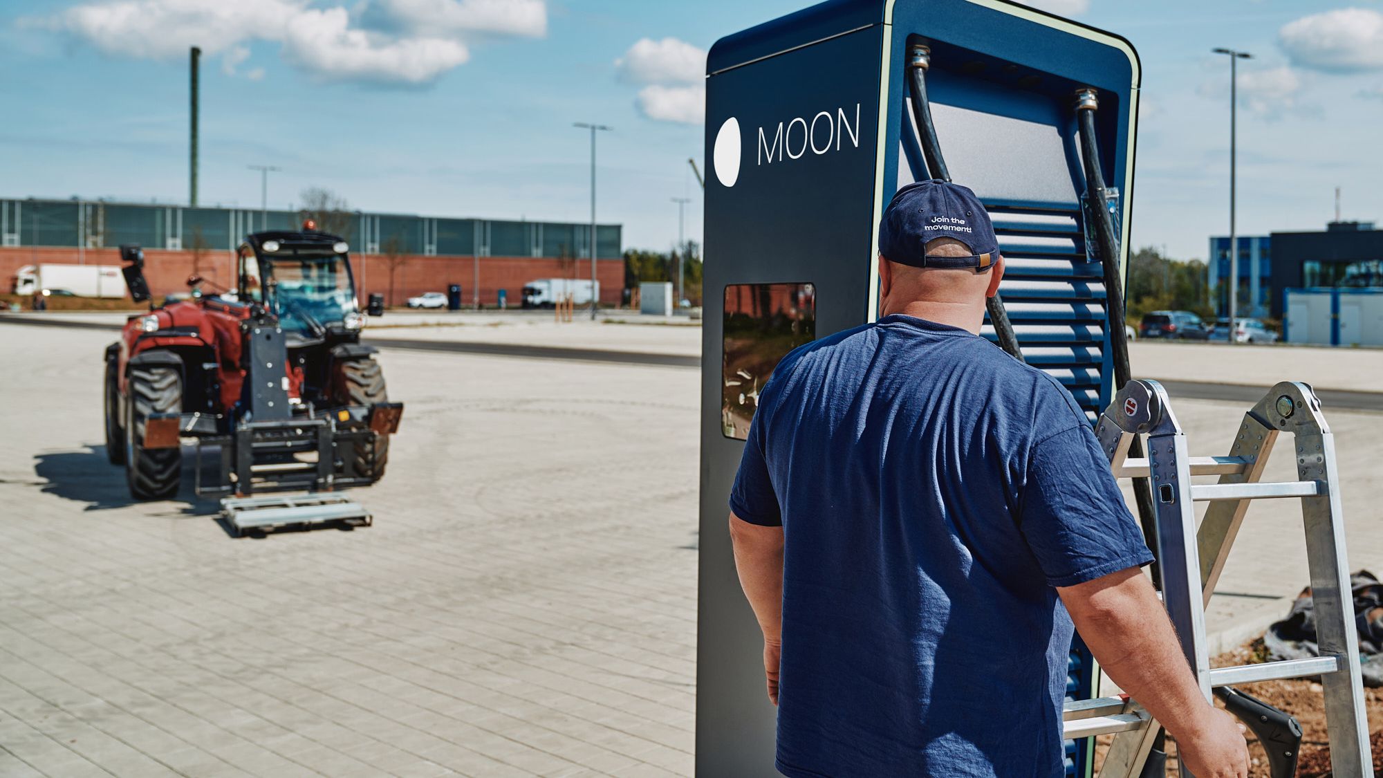A man stands with a ladder in front of the POWER Charger