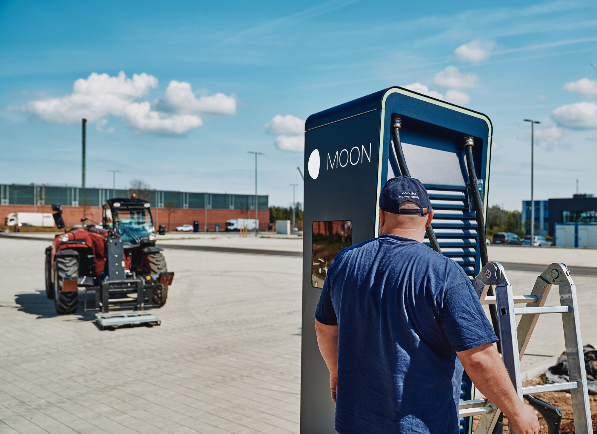 A man stands with a ladder in front of the POWER Charger