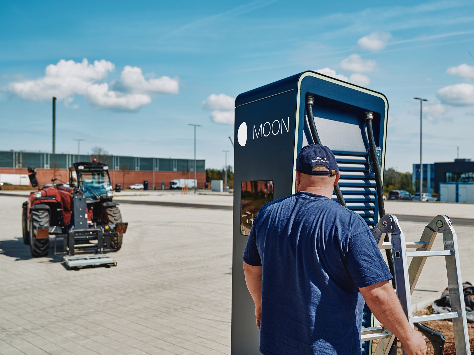 A man stands with a ladder in front of the POWER Charger
