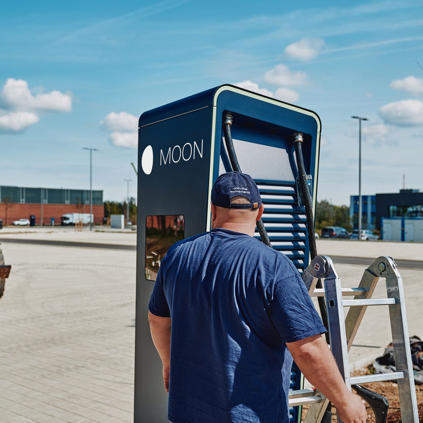 A man stands with a ladder in front of the POWER Charger