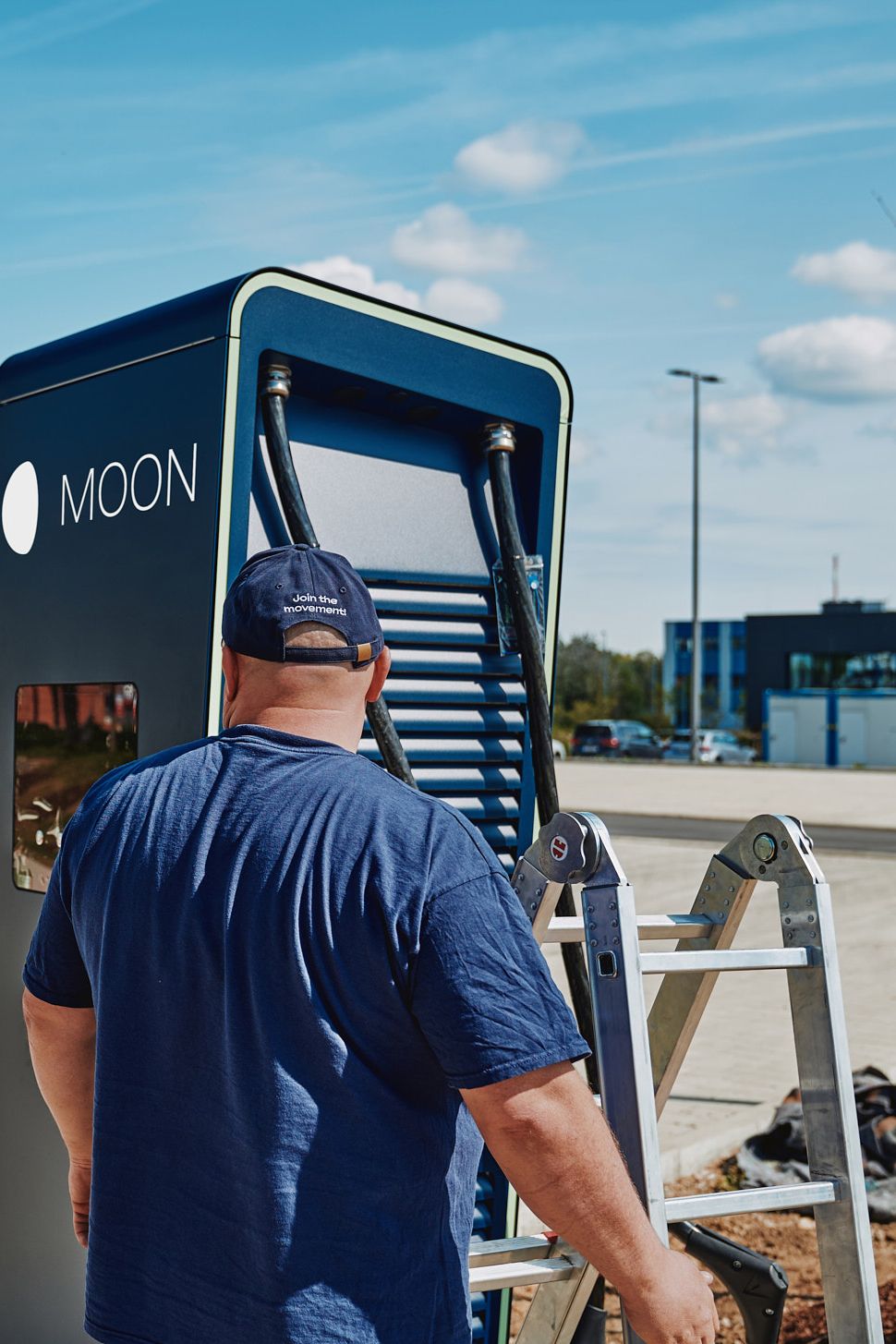 A man stands with a ladder in front of the POWER Charger
