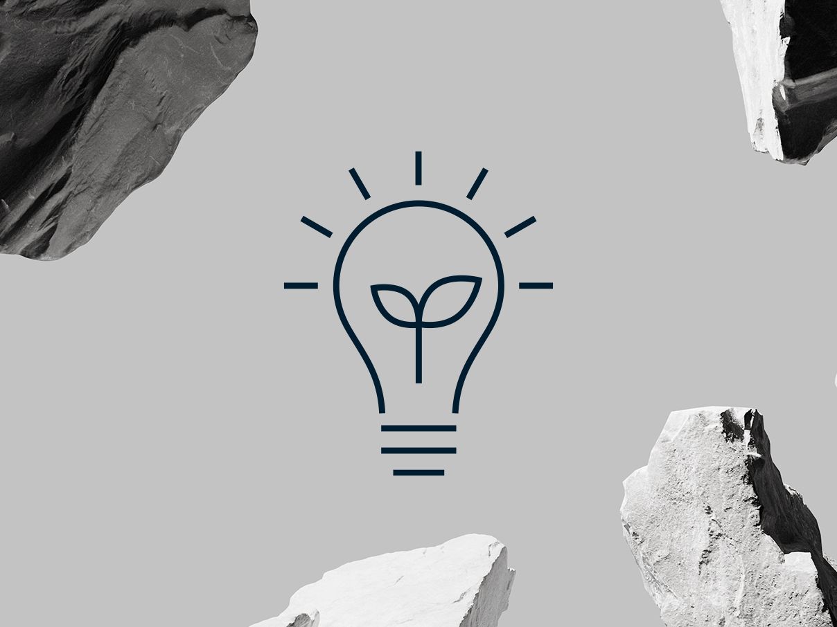 Light bulb icon against gray background with boulders