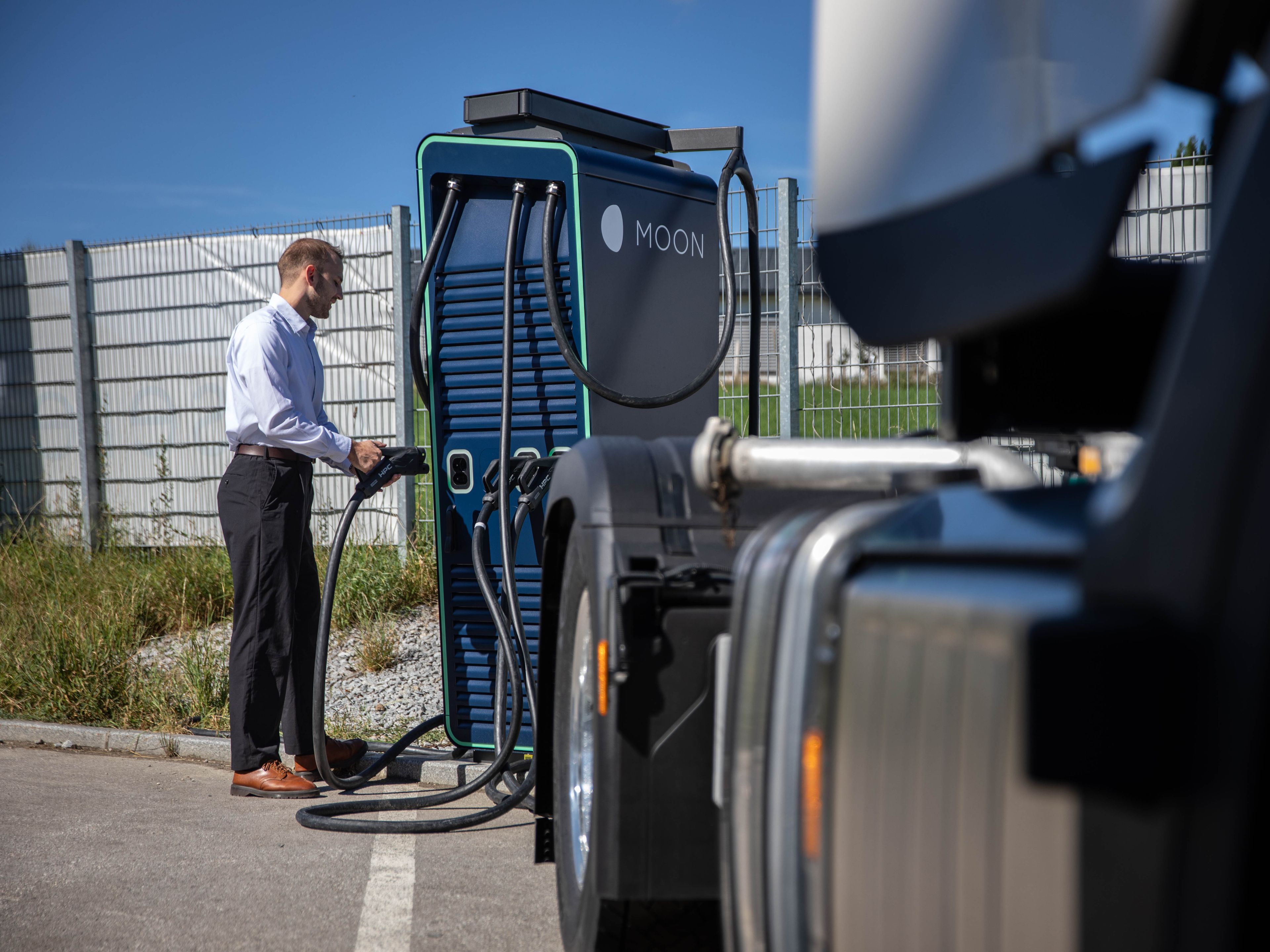 A man takes the plug of a HYC 200-400 fast charging station behind a truck