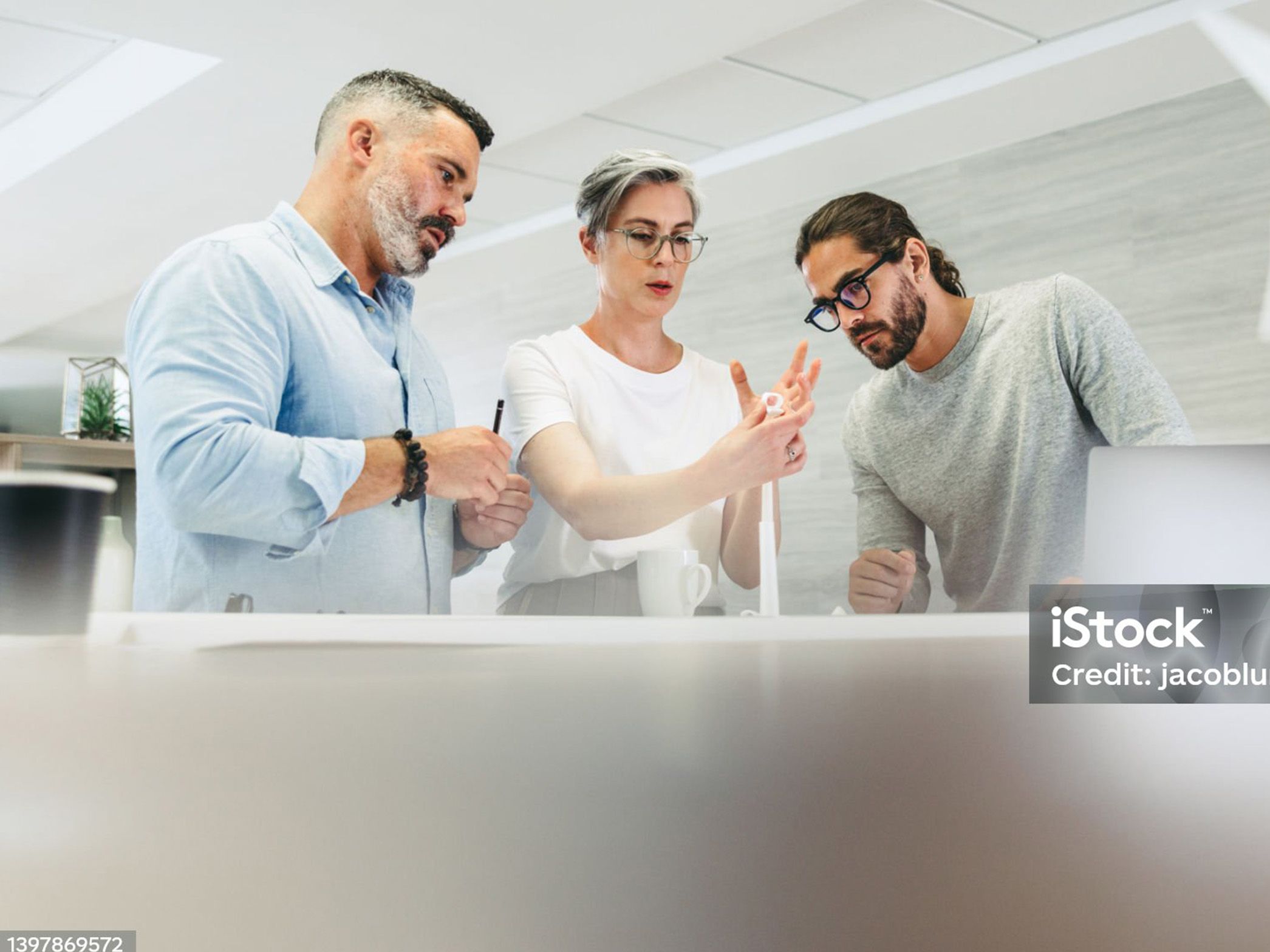 three people are standing at a table and looking at something