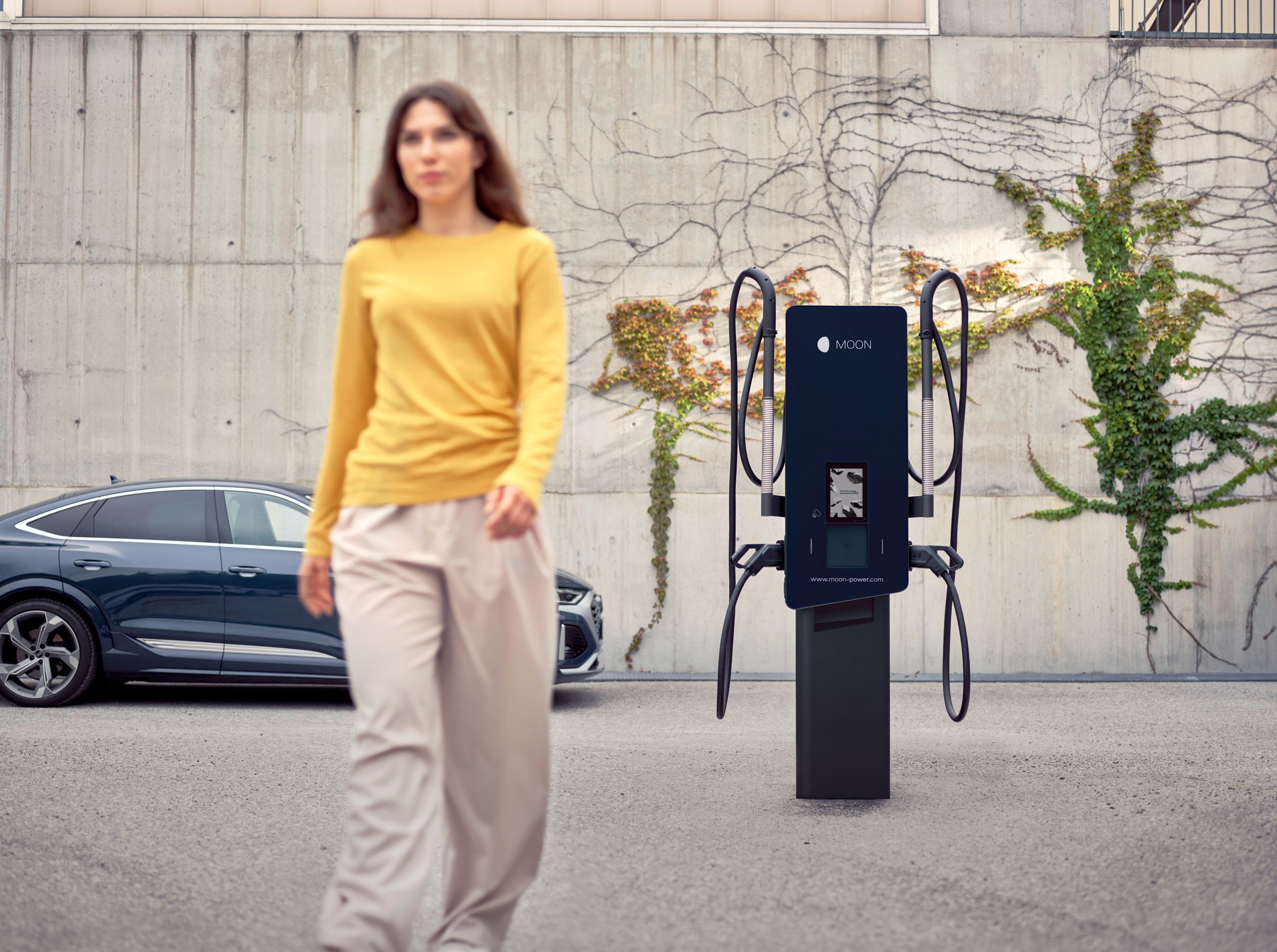 Frau geht von einer Ladestation vor einem Auto weg