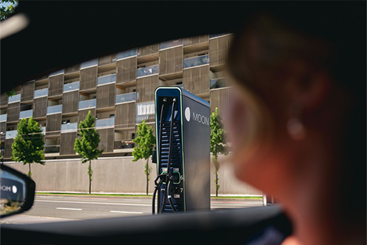 Person sitting in a car with charging station in the background