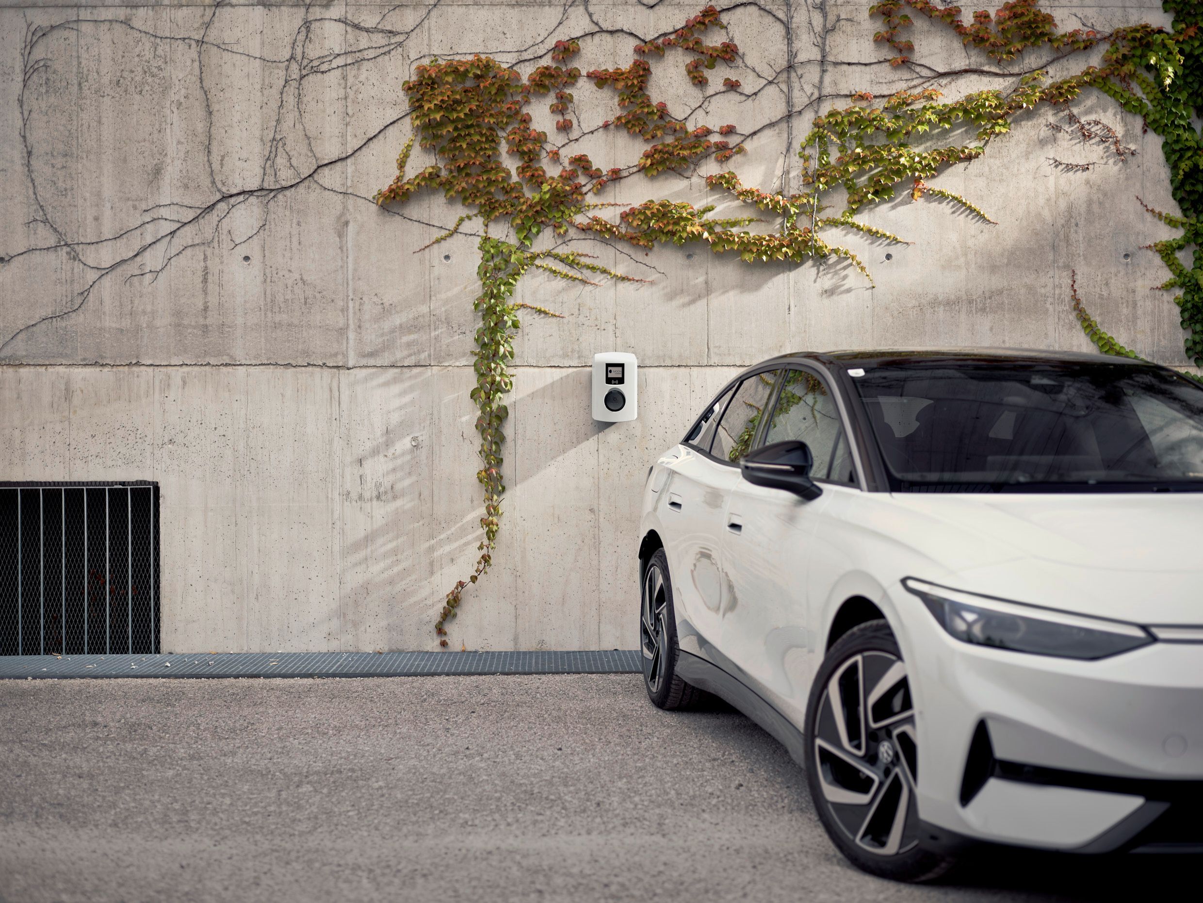 Car stands in front of a concrete wall with wallbox