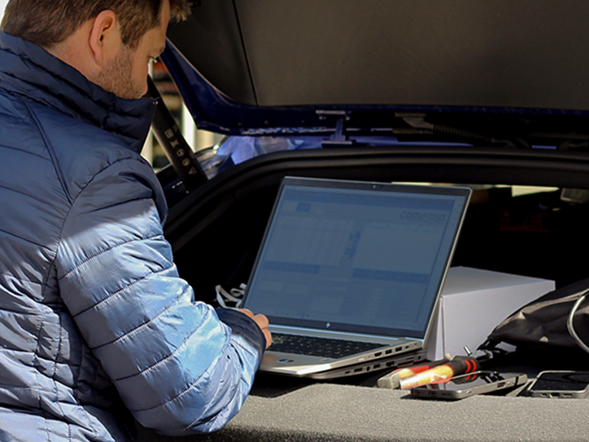 Homem com laptop em pé sobre a tampa de um porta-malas