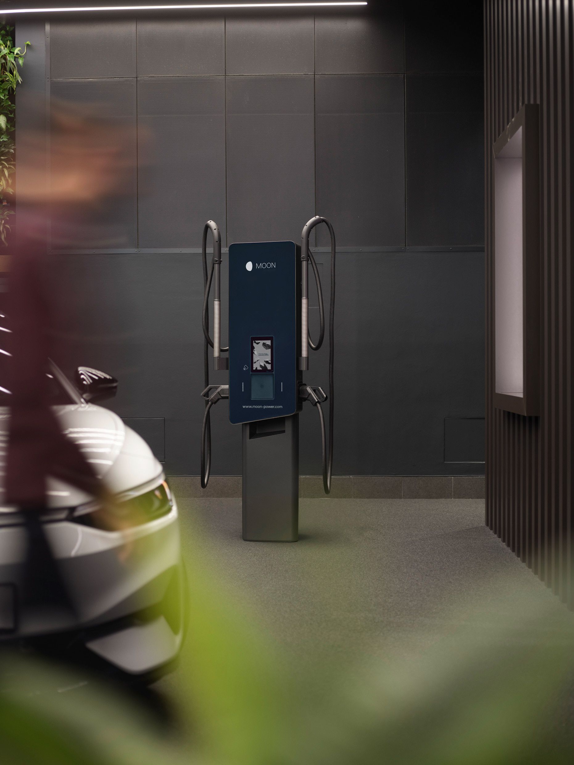 Ladestation in einem Raum mit grauen Wänden und einem Auto im Vordergrund